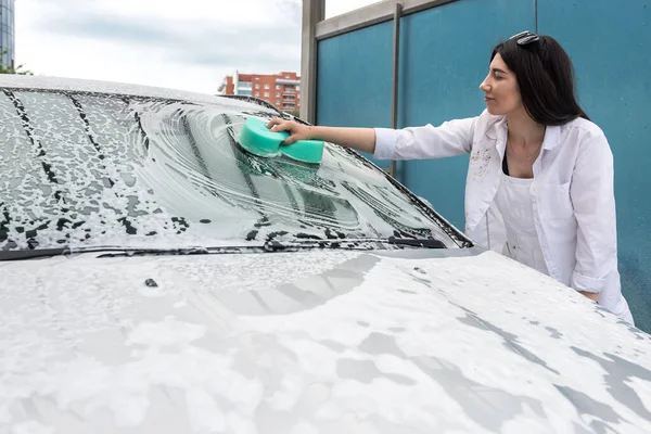 girl washes a car with a washcloth with foam. car cleaning