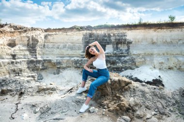 Çölün kumları arasında yürüyen genç bir kadın ya da mavi gökyüzü ile taş ocağı, doğada mükemmel bir yaşam tarzı.