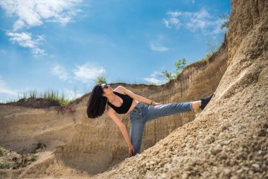 Genç bir kadın kum ocağında hafif egzersizler yapıyor. yoga. Doğada rahatlama. güneşli bir gün