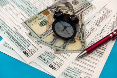 Vergi, saat kalemi ve dolar banknotlarıyla 1040 formunda. vergilendirme