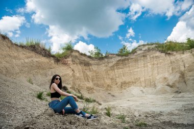 Seksi, güzel genç bir kadın, kum ocağında günlük giysiler giyiyor. Açık hava