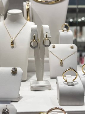 Altın kolyeler ve mücevher dükkanının vitrininde duran dimonlu küpeler. Kimse.