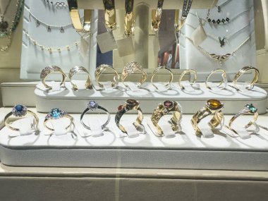  Mücevher dükkanında altın kolyeler, bilezikler ve küpeler olan bir vitrin. Alışveriş konsepti