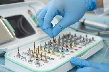 Randevu sırasında dişçi aletlerini seçen erkek dişçi ya da diş hekiminde çalışmaya hazırlanırken fırçayı cilalayan kişi