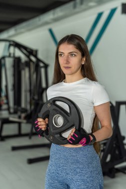 Sportif kadın spor salonunda ağır ağırlık plakasıyla antrenman yapıyor. Spor salonunda idman yapıyorum.