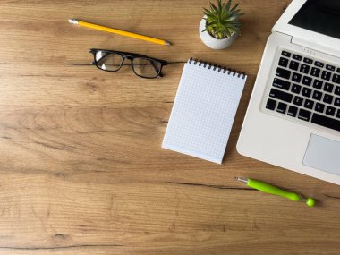 Dizüstü bilgisayarı olan bir iş yeri, ofis masasında boş defter ofis malzemeleri. Yaratıcı bir geçmiş. Düz yatıyordu