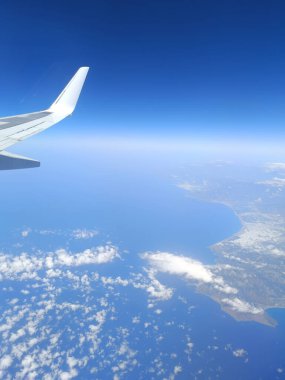 Derin mavi denizin üzerinde uçan uçak penceresinden kıyı manzarası