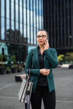 İş merkezinin yakınında dışarıda yürürken cep telefonuyla konuşan başarılı beyaz iş kadını.