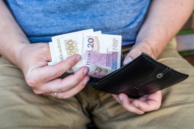 Cüzdan ve parayla Polonyalı Zloty 'lerin ellerini saymak. Siyah deri cüzdandan Polonya zloti paraları tutan ve sayan sıradan giysili bir adam..