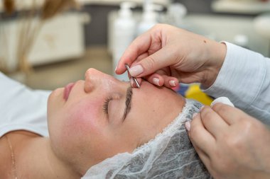 Güzellik uzmanı, güzellik salonundaki genç bayan müşteri tarafından manuel yüz temizleme yapıyor. Yaşlanma önleme prosedürleri