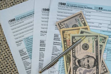 ABD gelir vergisi formları ve vergi sezonu için kalemle düzenlenmiş 100 dolarlık banknotlar.