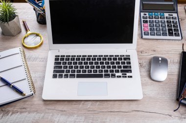 Ofis masası geçmişi, dizüstü bilgisayarı, boş not defteri, kalem hesap makinesi ve malzemeleri. Üst görünüm, iş geçmişi