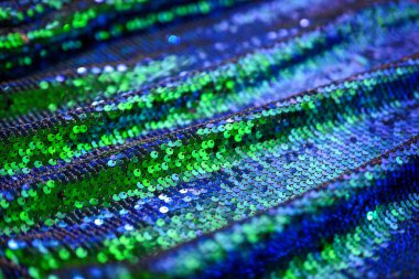 Blue and emerald sequin fabric close-up. Sparkling texture ideal for fashion projects, celebration design, luxury packaging, or party concept.