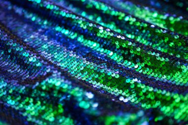 Abstract glitter background with blue and green sequins. Glitter background for fashion design, party decoration, or festive abstract backdrop. Shallow depth of field, soft focus.