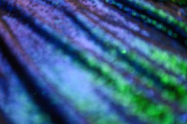 Blurred blue-green sequin fabric background with glossy surface and light reflections. Festive abstract backdrop for fashion projects, celebration design, party decoration or holiday theme.