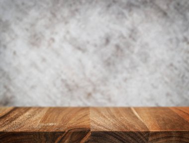 Ahşap masa yüzeyi ve bulanık beton duvar arka planı. Ürün gösterimi, maketi ya da tasarım sunumu için boş doğal ahşap masa. Doğal sıcak ahşap yüzey ve yumuşak ışık.
