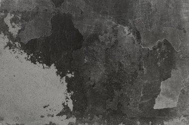 Boya deseni soyulmuş eski, koyu beton bir duvar. Çatlak ve yıpranmış lekeli kaba bir arka plan. Tasarım ve grafik için endüstriyel vintage arkaplan.