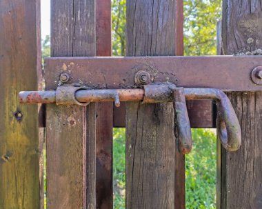 Eski paslı cıvata sürgüsü ahşap çitin mandalı. Yaklaş.