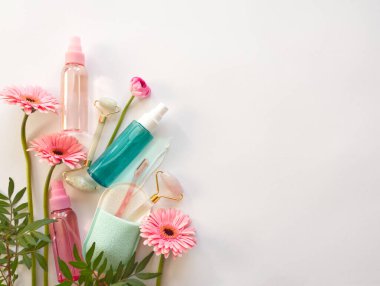 Kozmetik kaplama modelleri: tonik veya losyon için pembe ve mavi konteynır, yüz silindiri, beyaz arka planda doğal elementlerle sünger. Yüz bakımı konsepti. Kaplıca ve banyo aletleri.. 