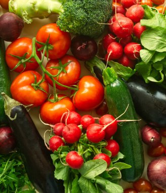 Çiğ taze sebze arka planı. Sağlıklı besinler ahşap arka planda yatıyordu. Organik kırmızı ve yeşil sebze çeşitleri: domates, turp, brokoli, patlıcan, salatalık, roka, kırmızı soğan, brokoli. Ahşap arkaplan. 