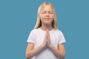 Göğüs hizasında avuçlarını tutan sakin bir kız.