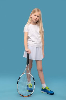 Kız elini tenis raketine yaslıyor.