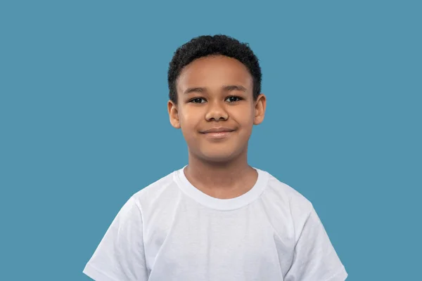 Smiling friendly dark-skinned boy on light blue background — Φωτογραφία Αρχείου