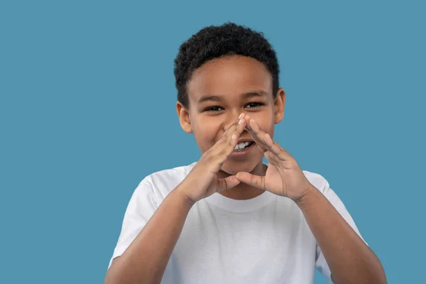 Joyful darkskinned boy holding hands near his mouth — Φωτογραφία Αρχείου