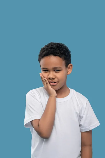 Sorglig afrikansk amerikansk pojke som håller i kinden — Stockfoto