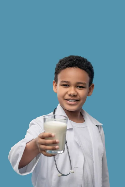 Glücklicher Junge im Laborkittel mit Glas Milch — Stockfoto