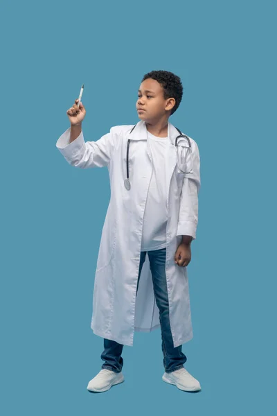 Niño en bata de laboratorio siguiendo el puntero con sus ojos — Foto de Stock