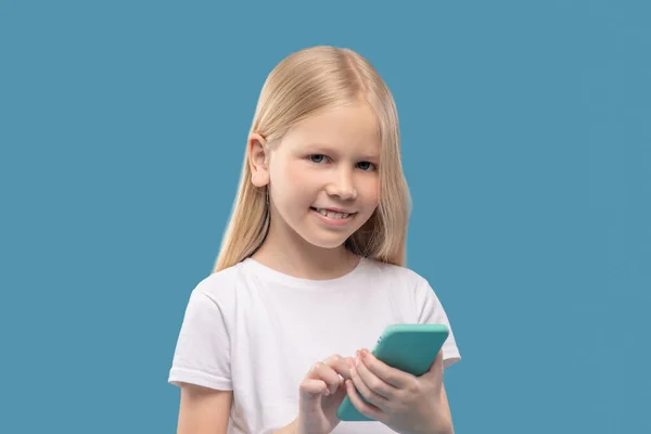 Chica alegre con teléfono inteligente en sus manos — Foto de Stock