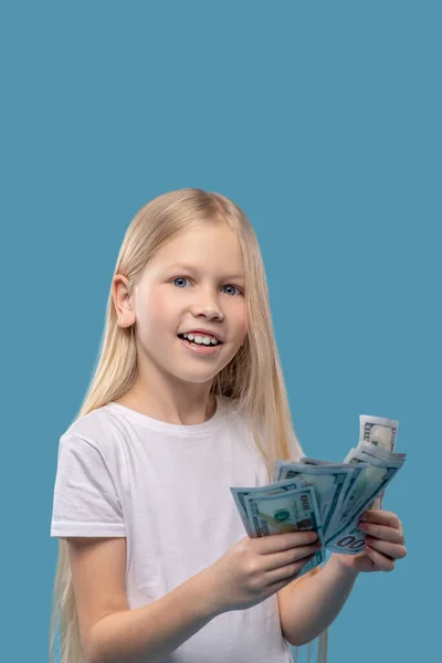 Chica sonriente de pelo largo sosteniendo billetes en las manos — Foto de Stock