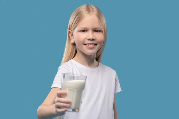Kleines Mädchen reicht Glas Milch nach vorne — Stockfoto