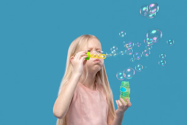 Adorable chica rubia soplando burbujas de jabón — Foto de Stock