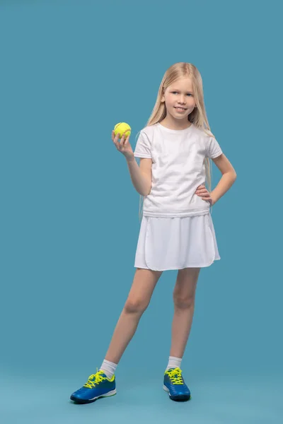 Dziewczyna w białej odzieży sportowej z piłką tenisową — Zdjęcie stockowe