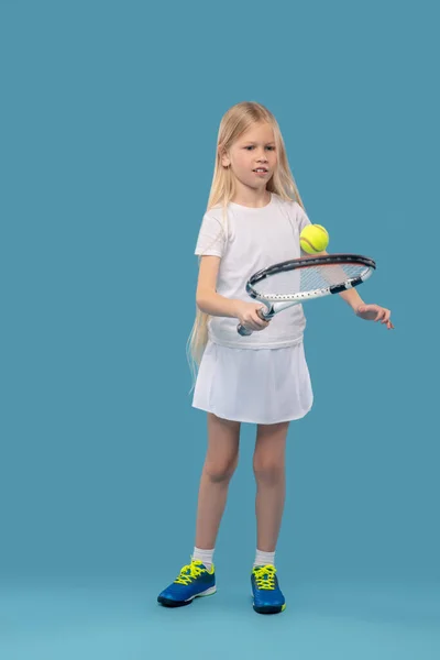 Girl exercising with tennis racket and ball