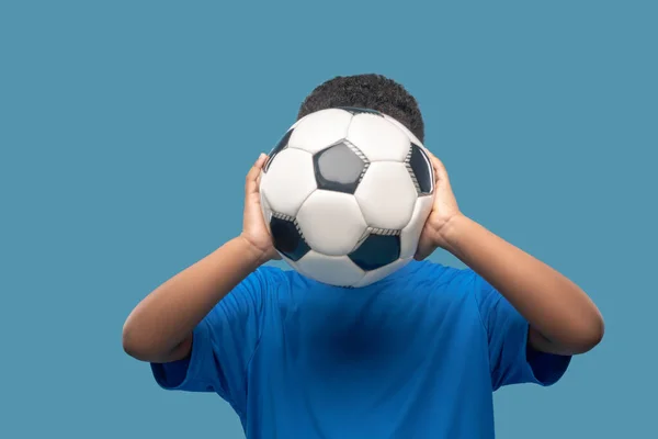 Menino segurando bola de futebol no nível do rosto — Fotografia de Stock