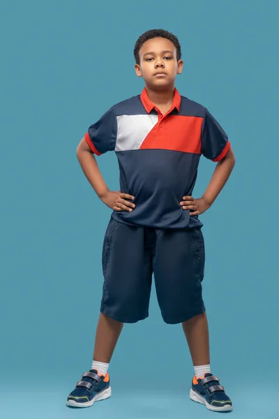 Ciemnoskóry chłopiec w odzieży sportowej na niebieskim tle — Zdjęcie stockowe