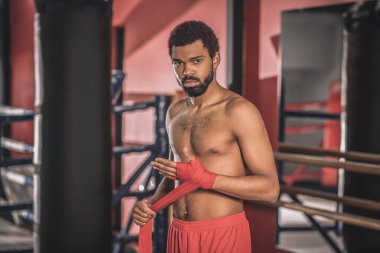 Afrika kökenli Amerikalı kickboksör antrenmandan önce eline bandaj yapıştırıyor.