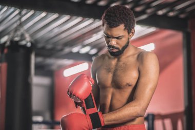 Koyu tenli sporcu ellerini kırmızı bandajla yazıyor.