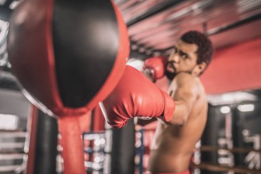 Afrikalı Amerikalı kickboksör spor salonunda antrenman yapıyor ve konsantre görünüyor.