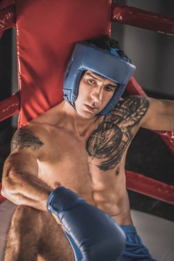 Mavi etekli genç kickboksör kavgadan sonra yorgun görünüyor.