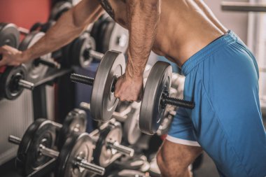 Göğsünde dövmesi olan genç bir adam spor salonunda çok çalışıyor.