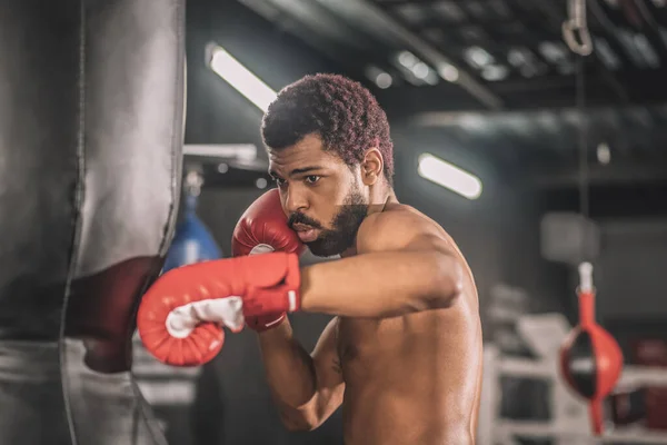 Koyu tenli genç kickboksör spor salonunda antrenman yapıyor. — Stok fotoğraf