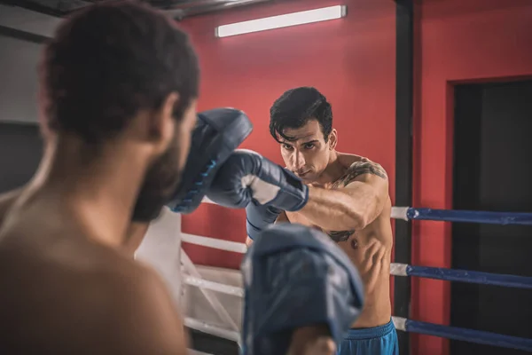 Mladí muži bojují na boxerském ringu a vypadají odhodlaně — Stock fotografie