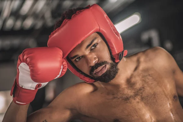 Dark-skinned kickboxer in a red hemlet looking tired after the fight — Stock Photo, Image