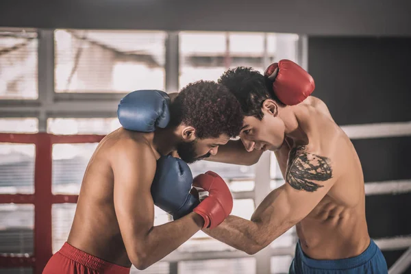 Deux hommes en tenue de sport faisant de l'exercice sur un ring de boxe et regardant impliqué — Photo