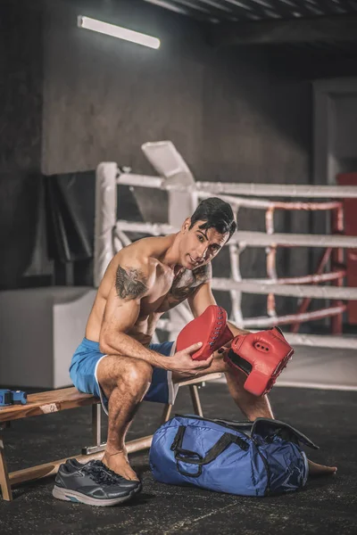 Muscular build man sitting in a changing room in a gym