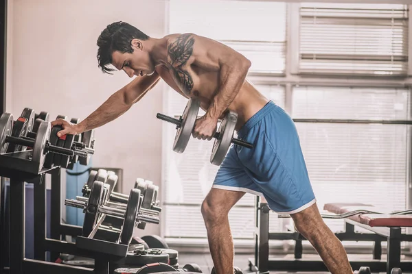 Göğsünde dövmesi olan genç bir adam spor salonunda çok çalışıyor. — Stok fotoğraf